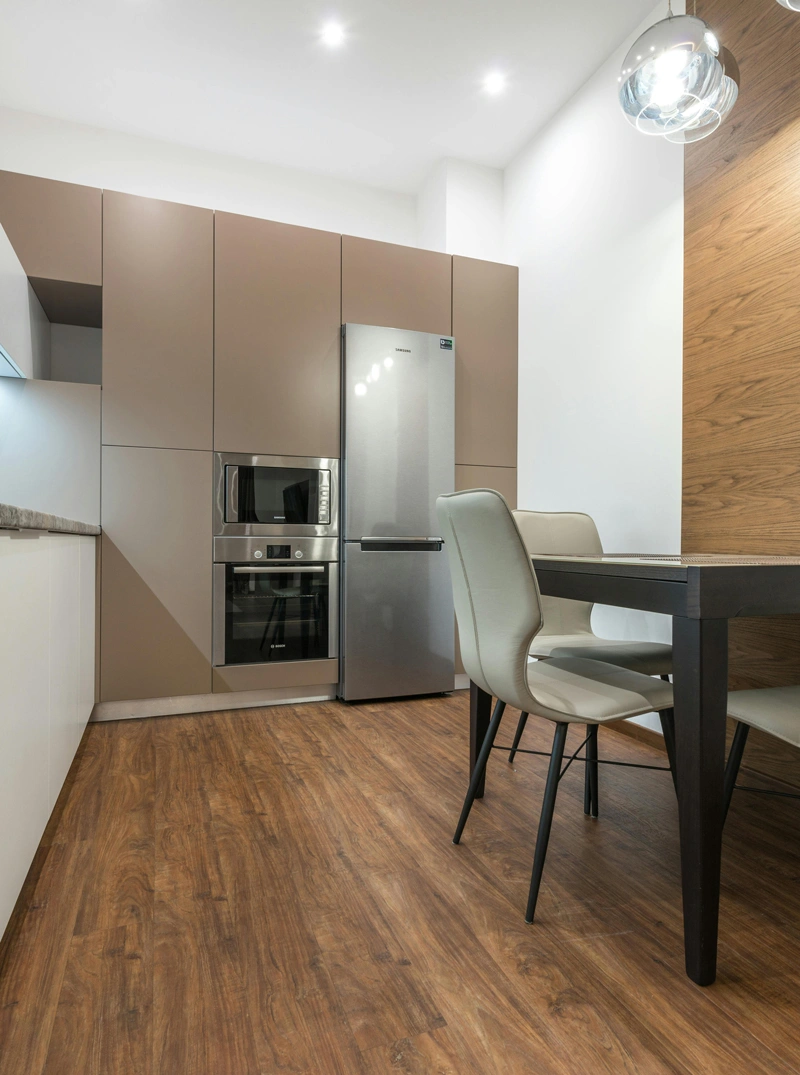 Moderna cucina con elettrodomestici in acciaio inossidabile e pavimento in legno, ideale per ambienti residenziali.