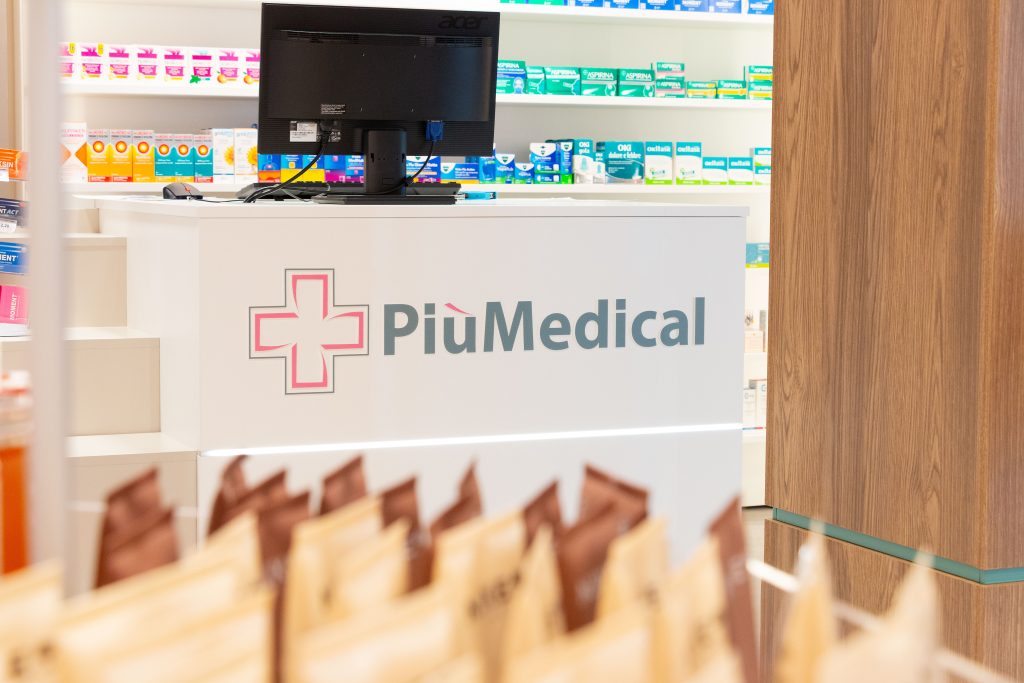 Modern pharmacy interior featuring the PiùMedical logo and a display of over-the-counter products.